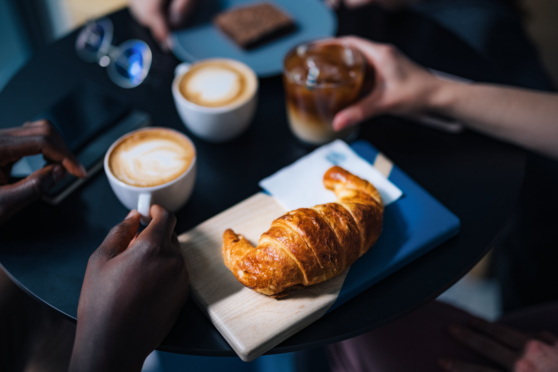 People drinking coffee and eating a croissant