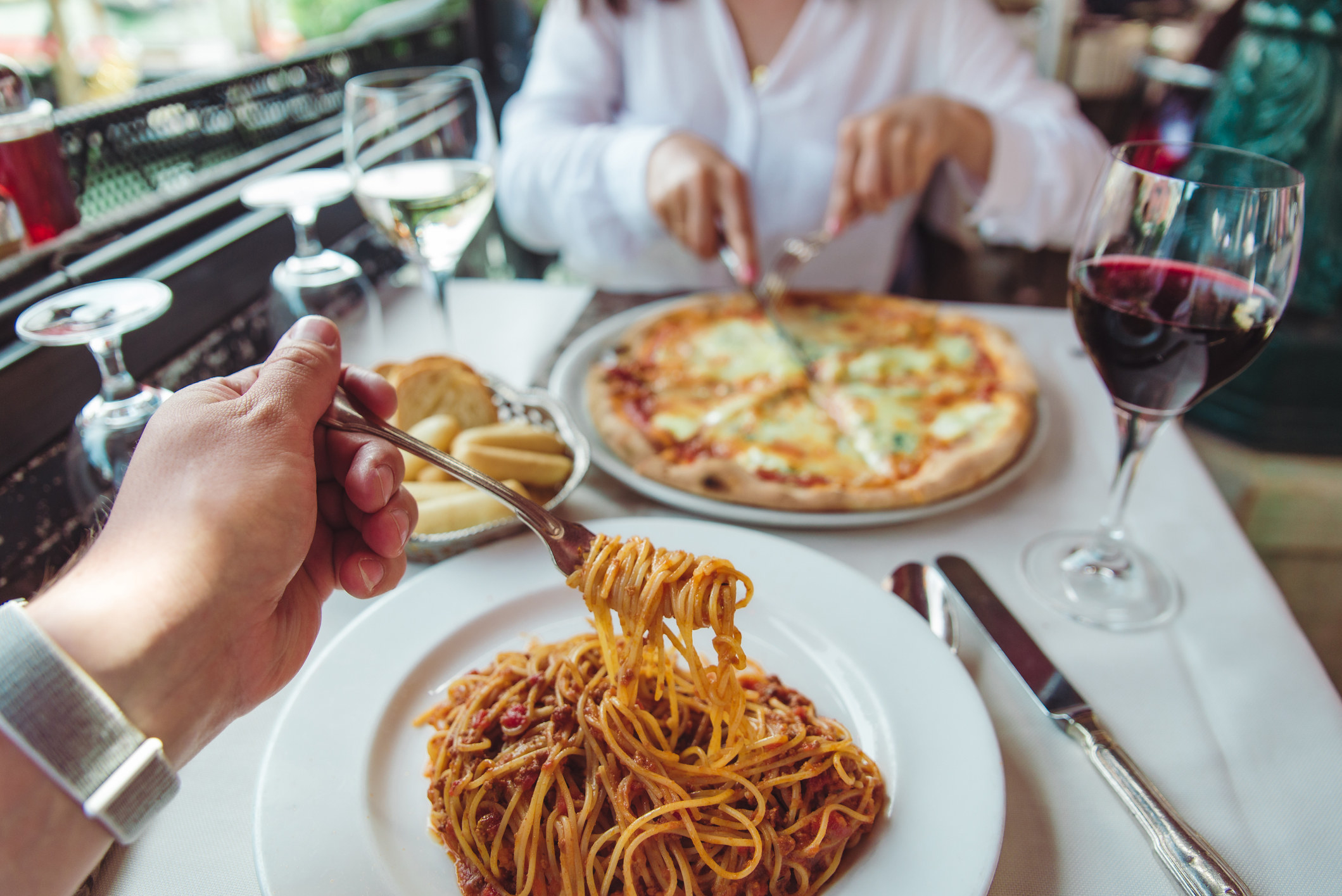 A couple eating Italian food and drinking wine