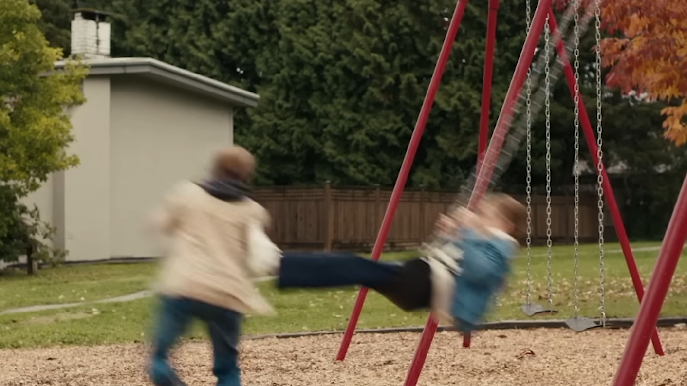 The boy gets kicked by another kid on the swing