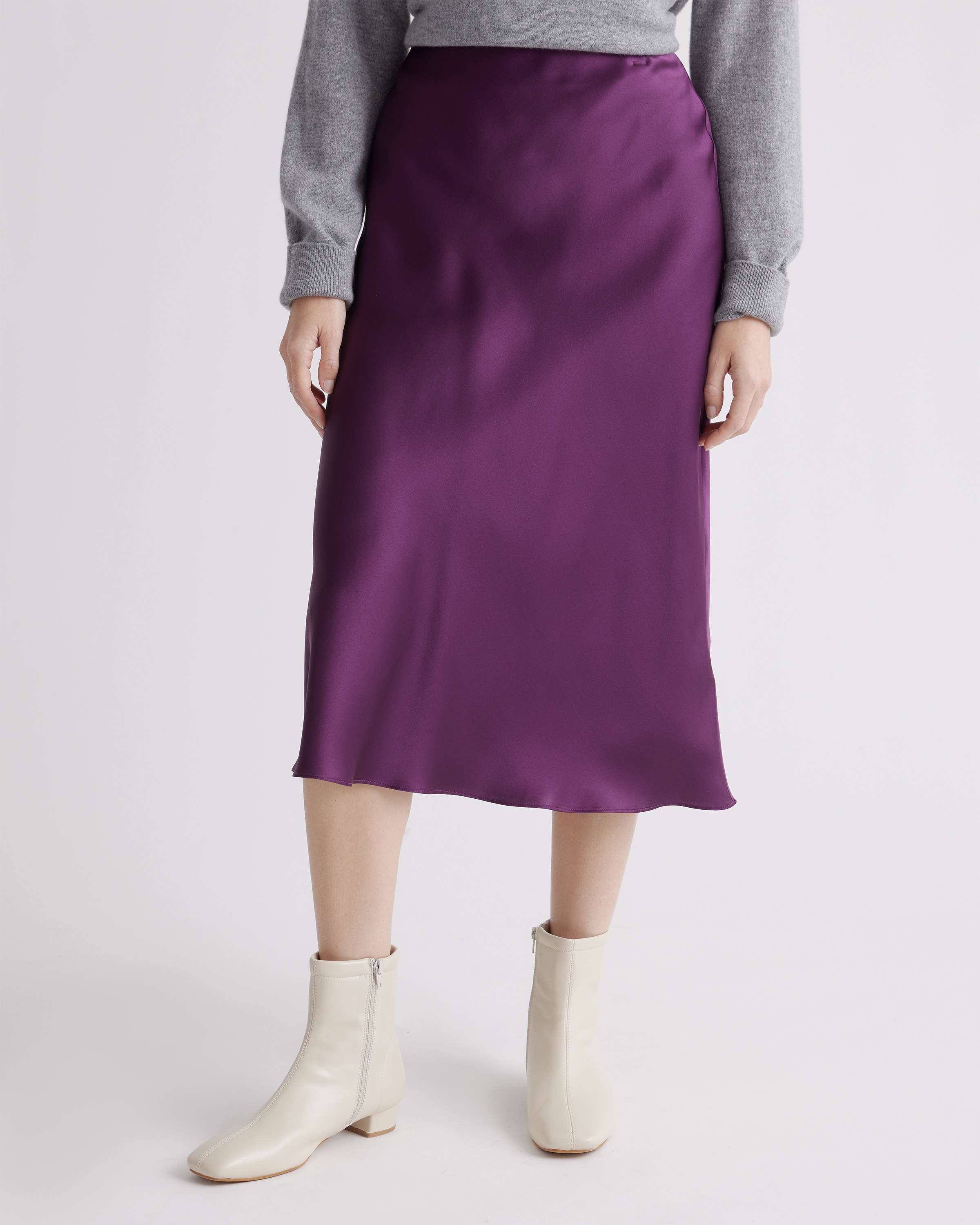 A model wearing a purple skirt with grey top and white shoes
