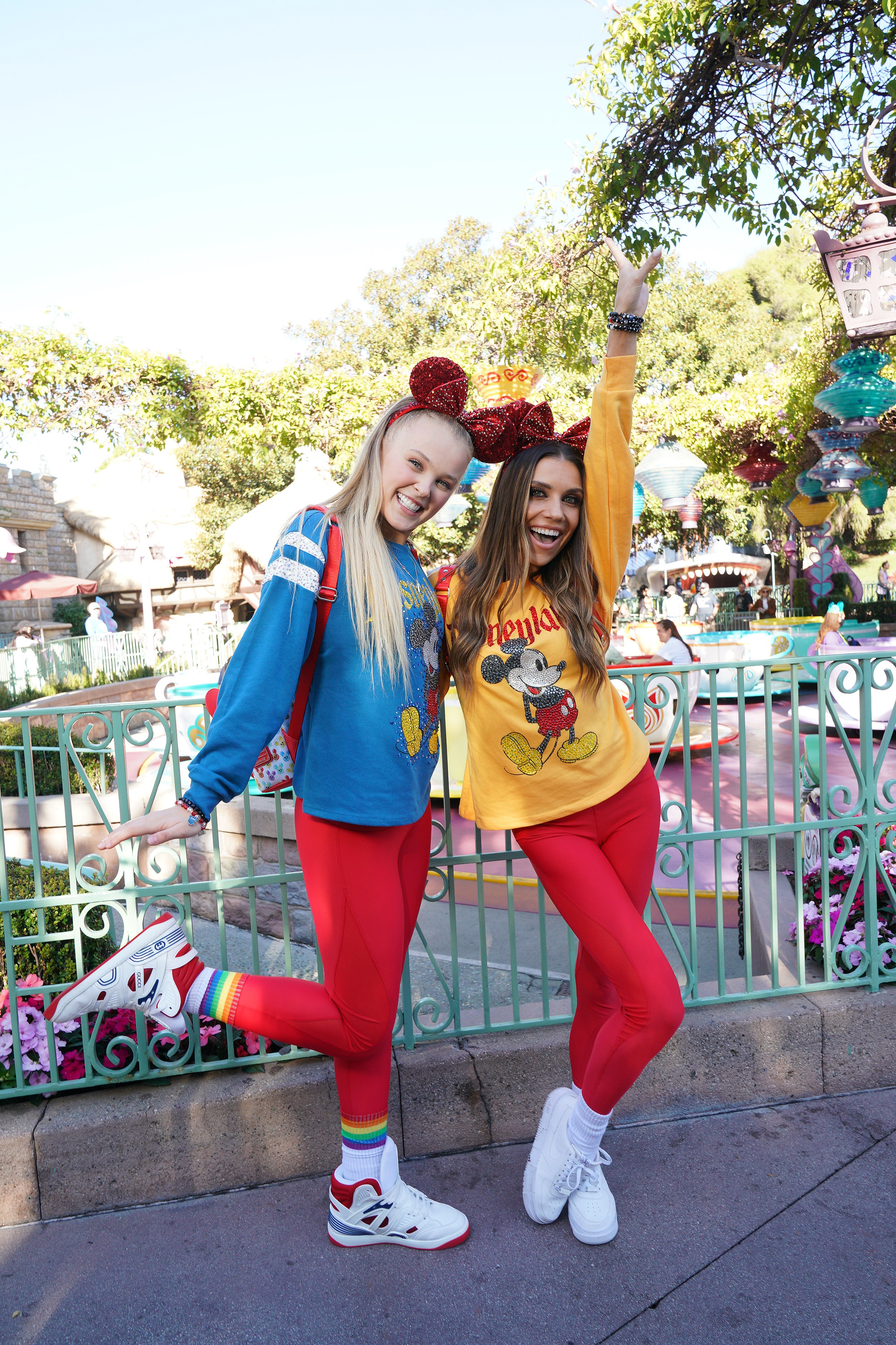 JoJo and a friend posing enthusiastically for a photo against an iron-wrought fence at Disney World