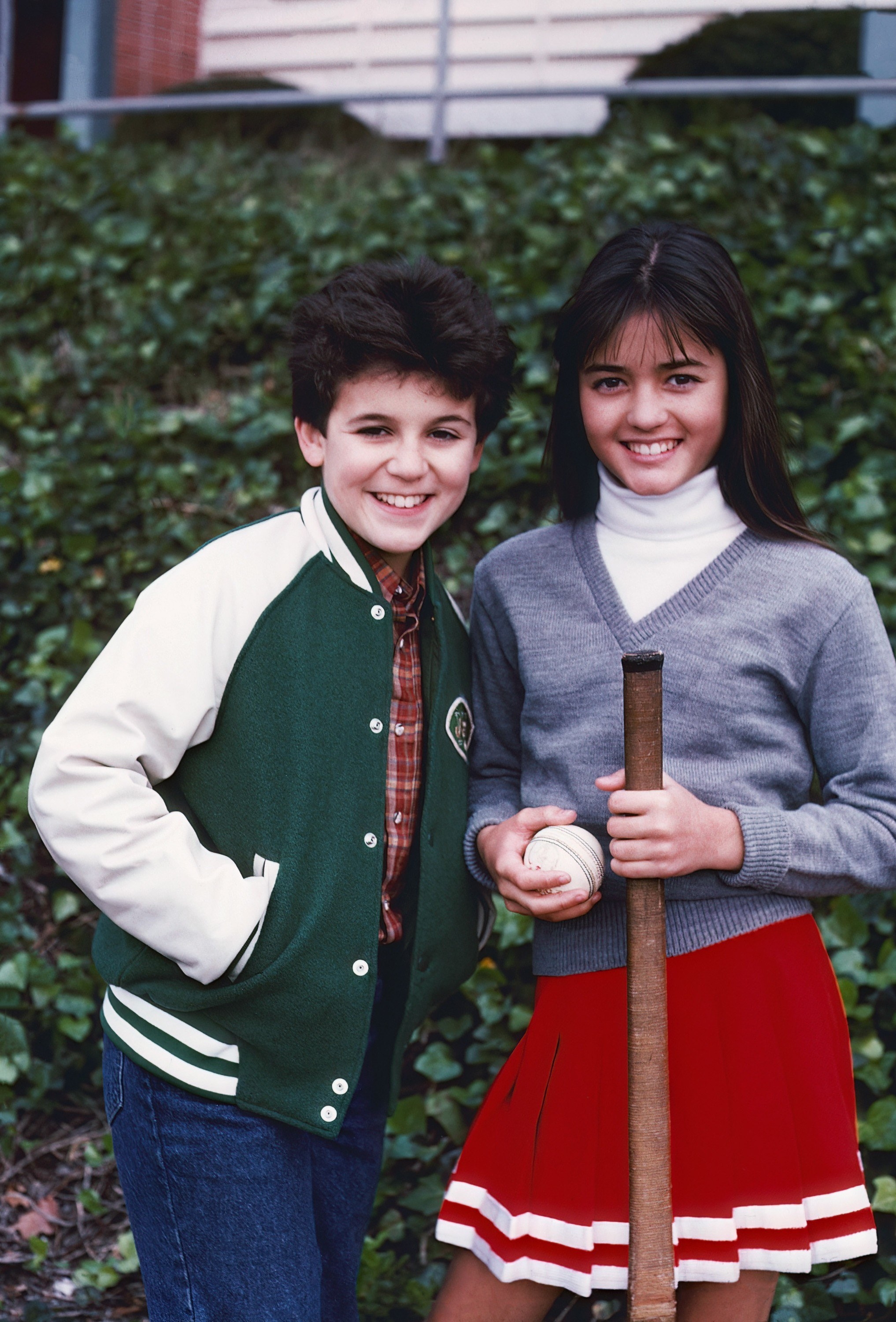 A throwback promo photo of Winnie on the right and Fred Savage on the left. They&#x27;re standing outside wearing baseball-inspired outfits