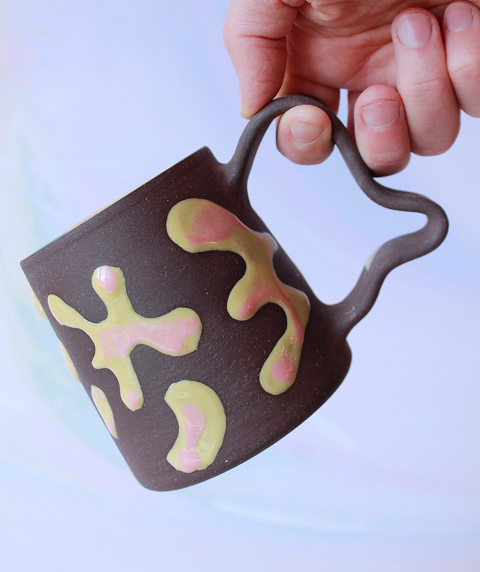 a person holding the psychedelic mug by its handle
