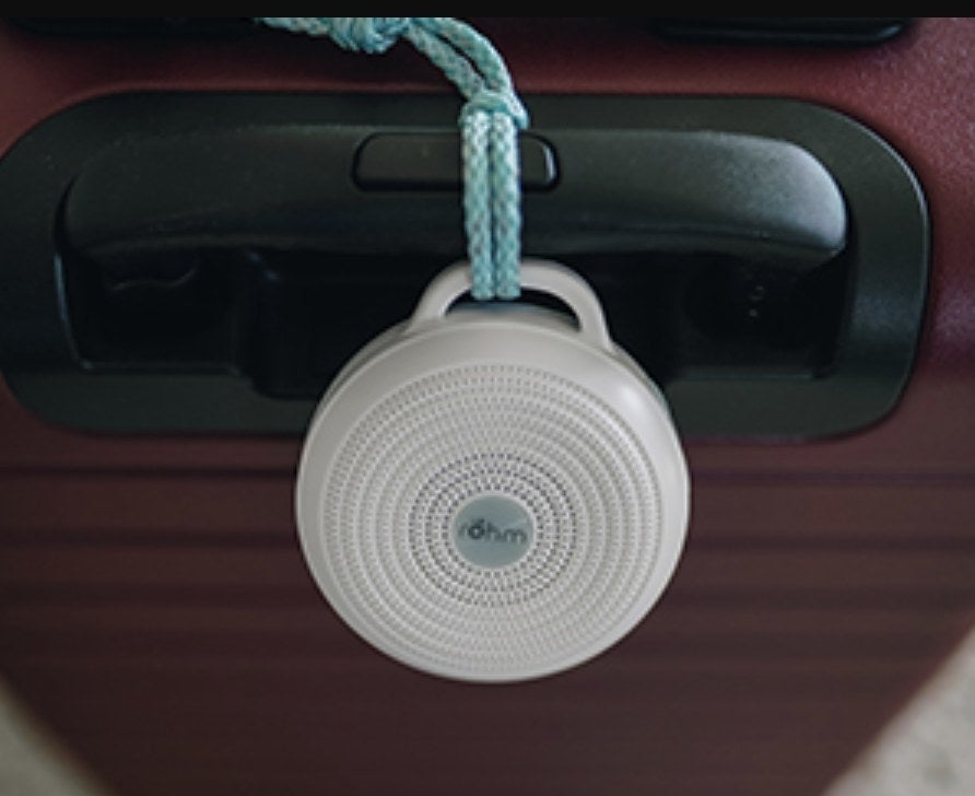 the small circular noise machine attached to the handle of a suitcase