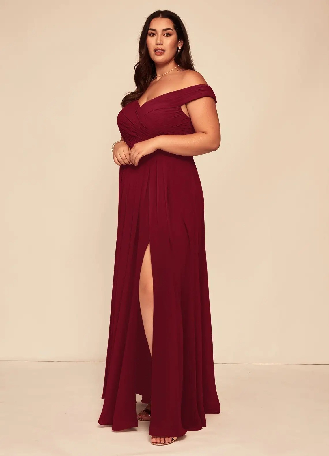 a model in an off the shoulder burgundy dress with a slit up the middle