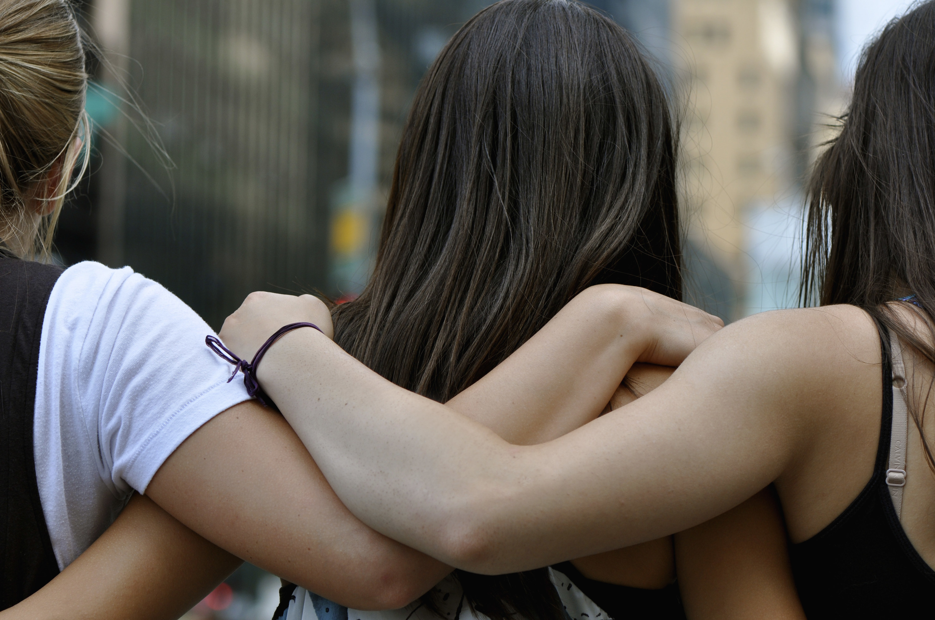 Three girls stand side by side with their arms around each other