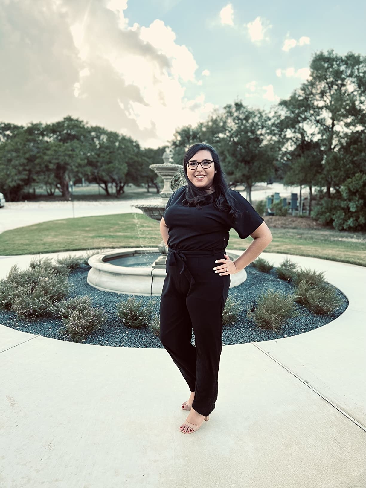reviewer posing in the black romper in front of fountain
