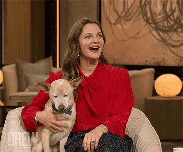 Drew Barrymore on her talk show petting a dog and smiling
