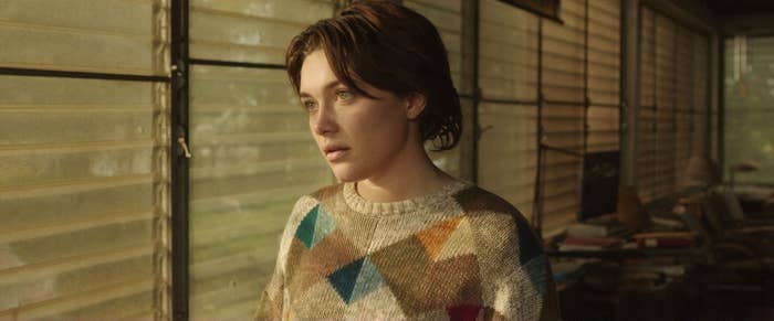 A closeup of Florence with short brown hair in a scene from A Good Person. She is wearing a sweater and looking out of a window