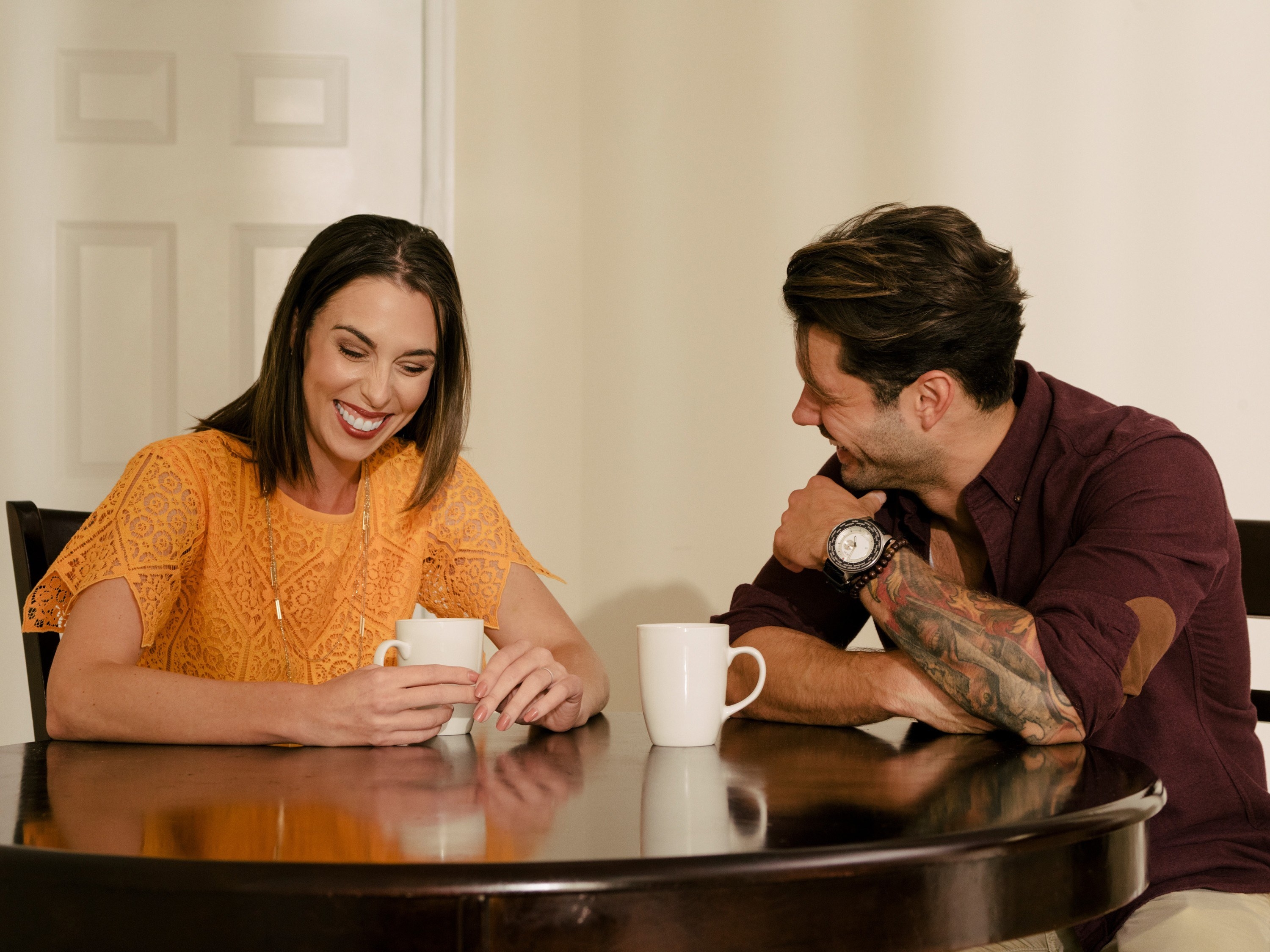 A man and a woman sit at a table, laughing together
