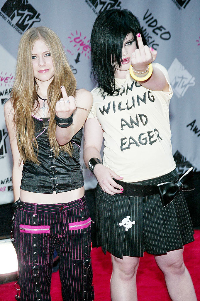 Avril Lavigne and Kelly Osbourne are giving the camera the finger on the red carpet; Kelly is wearing a &quot;Young Willing and Eager&quot; T-shirt