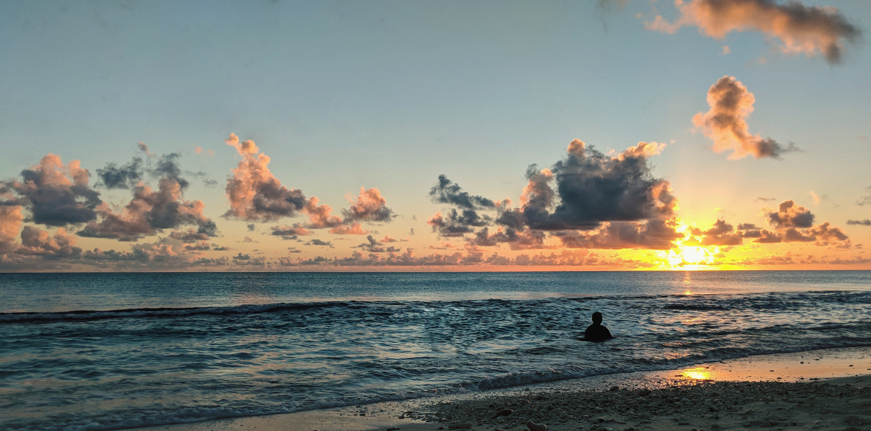 A person in the ocean at sunset.