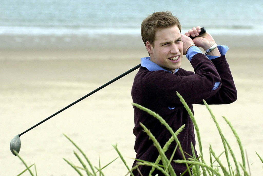 He&#x27;s looking in the distance for the ball and smiling, the iron over his shoulder, with the sand and sea behind him