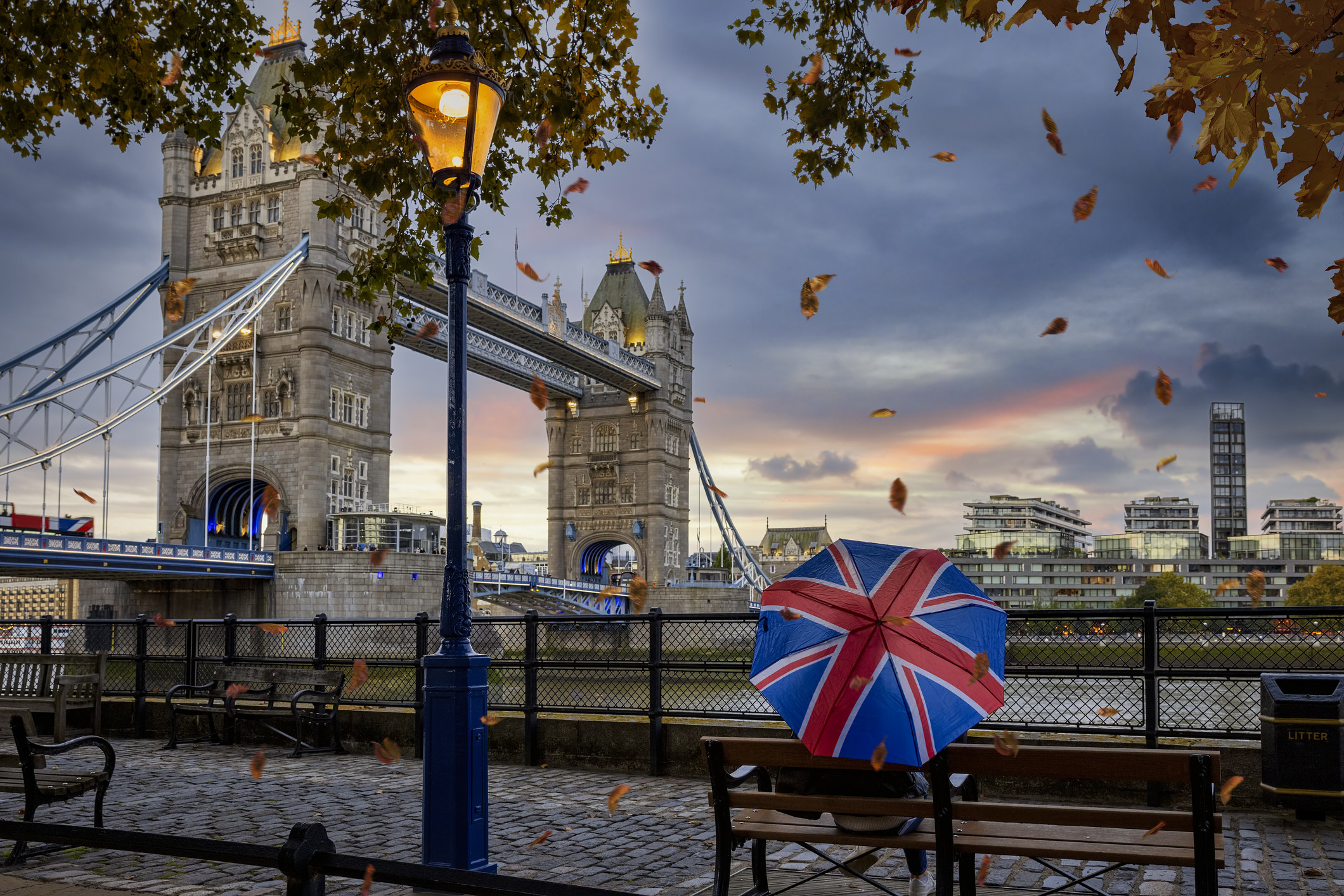 A person standing in front of Tower Bridge with an umbrella.
