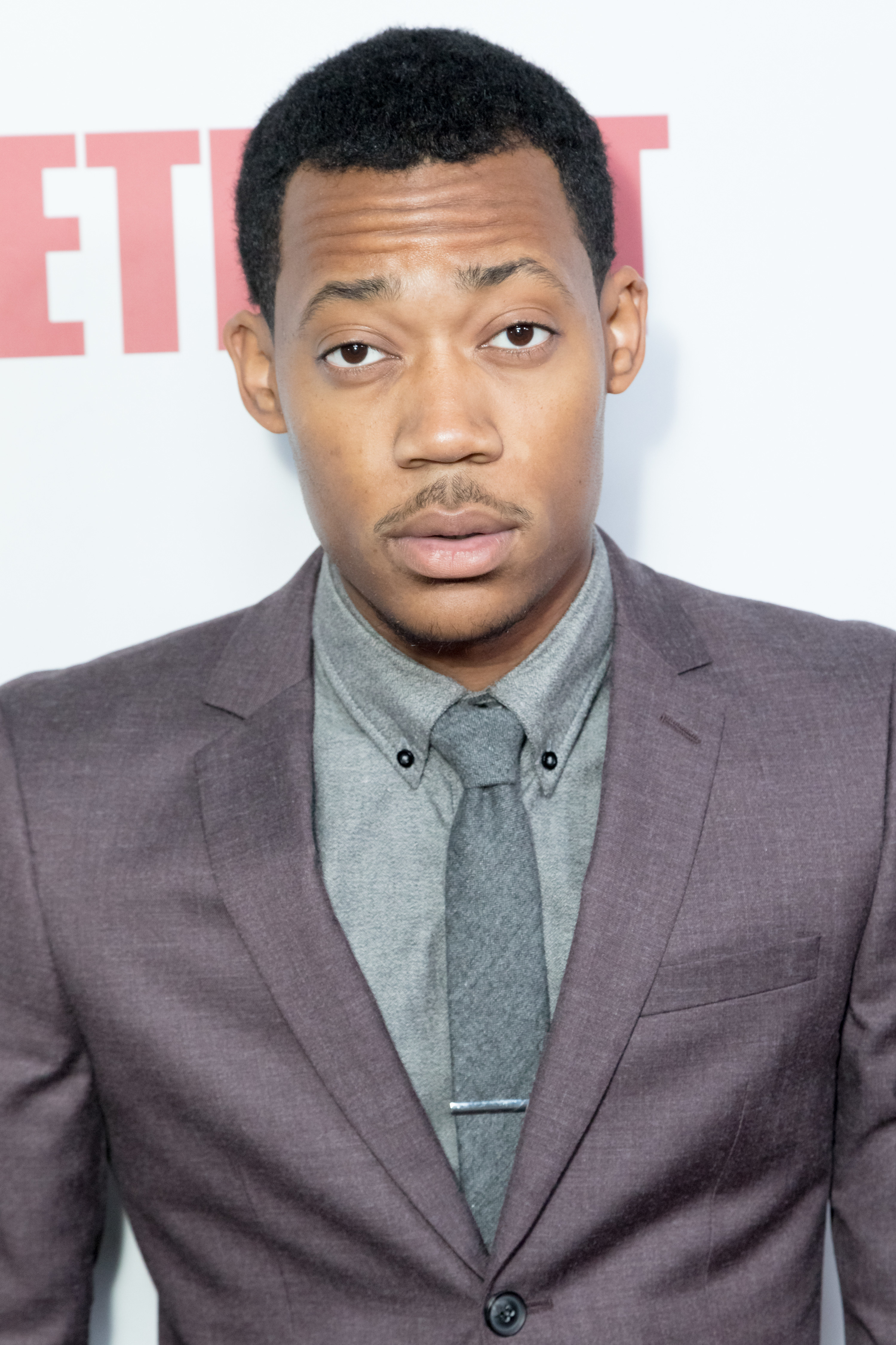 A closeup of an adult Tyler in a tailored suit and tie