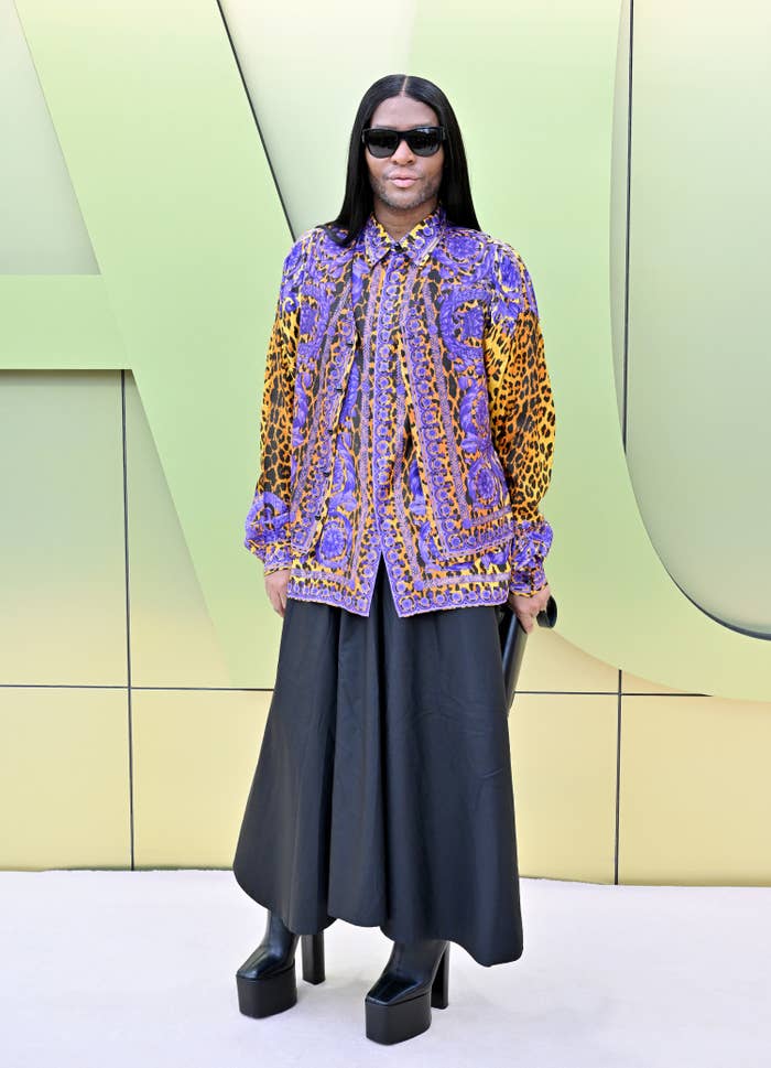Law Roach in a long skirt, animal print blouse, and platform shoes