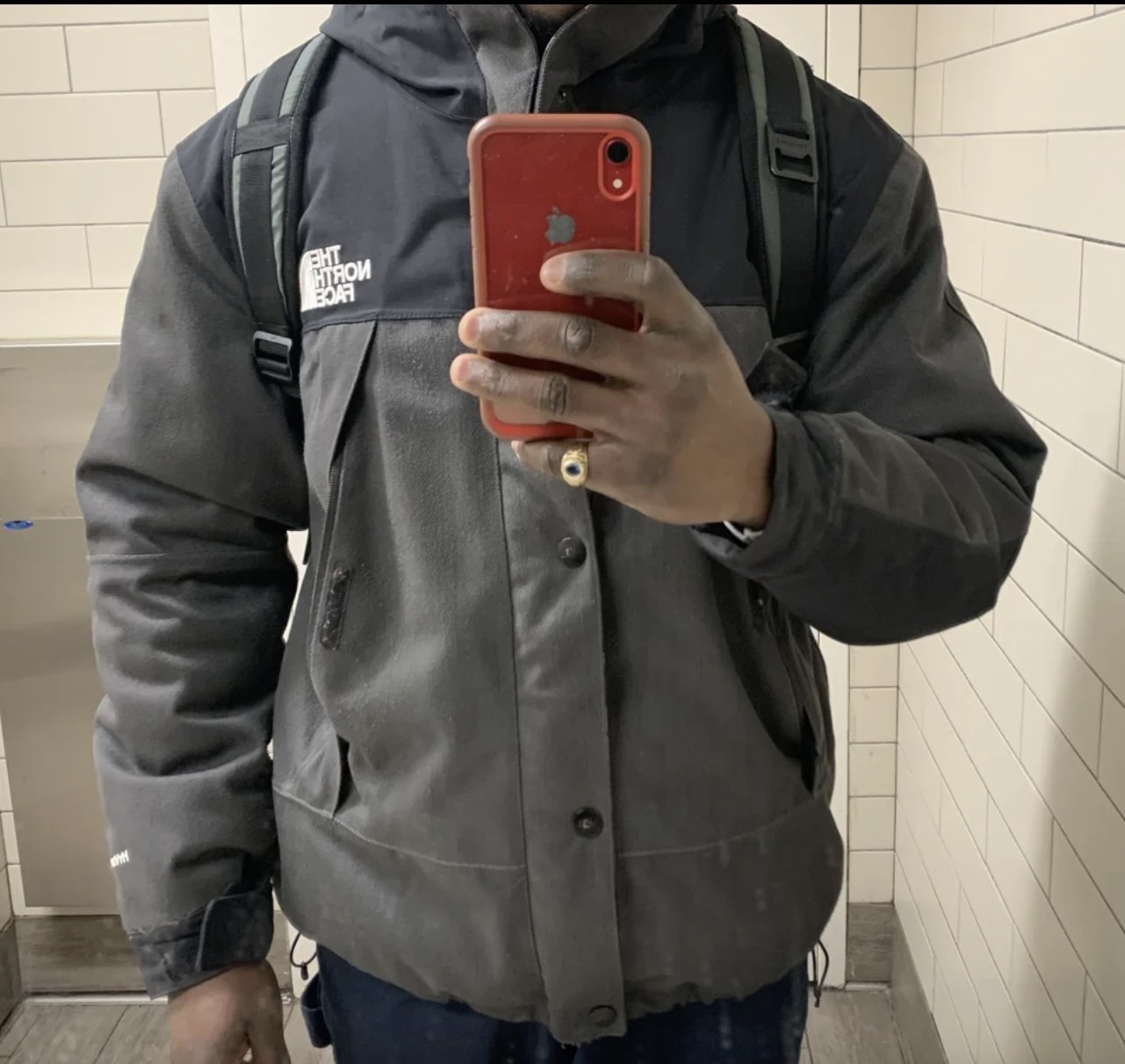 man in a gray North Face jacket takes selfie in mirror