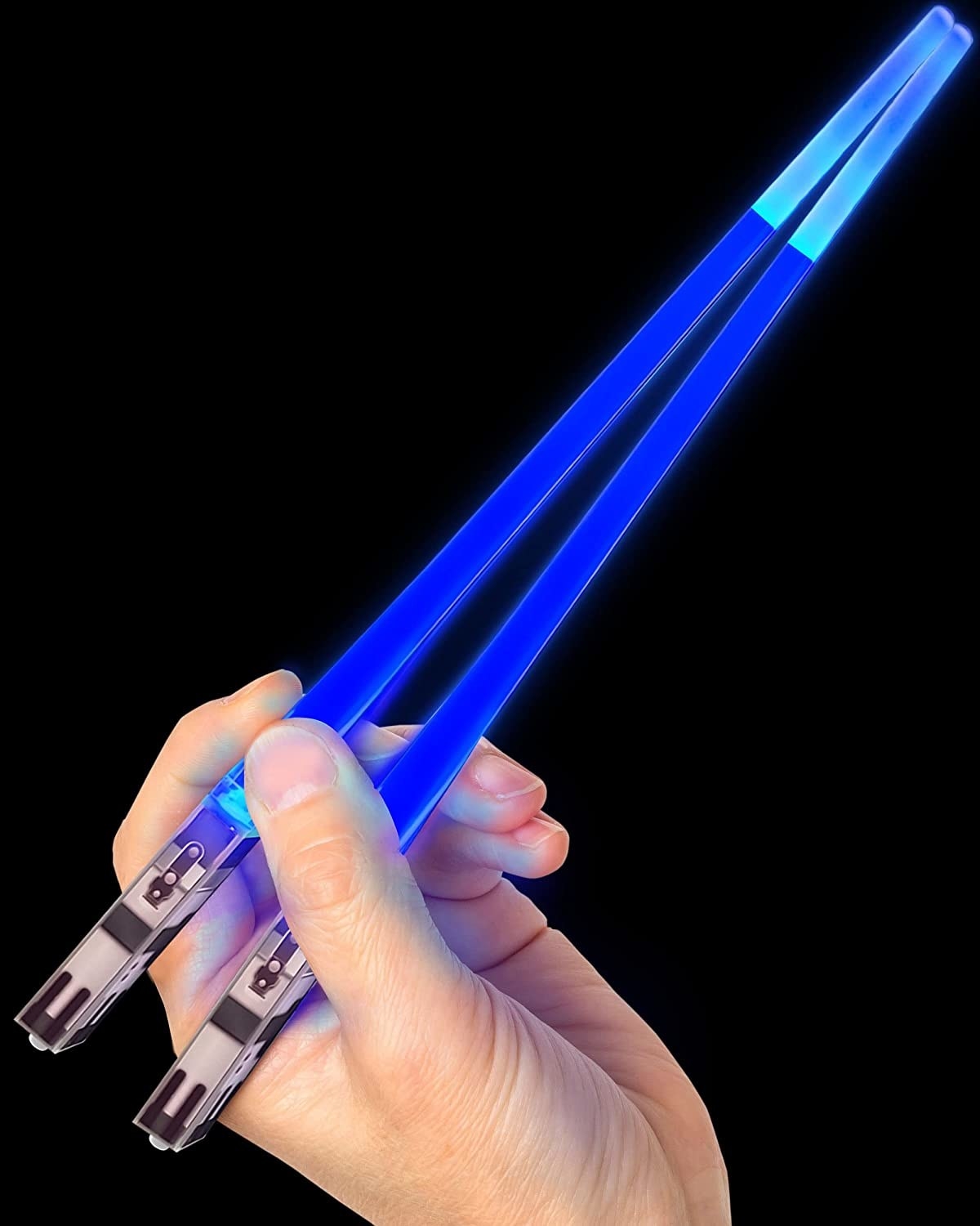 a person holding up the light up chop sticks in front of a dark background