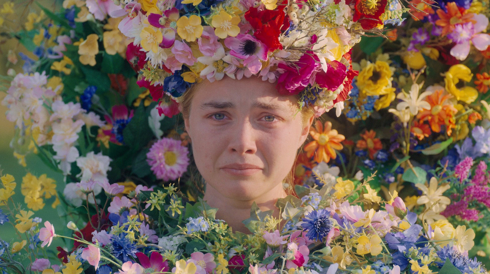 Florence Pugh wearing a flower crown and a flower dress with a frown on her face at the end of &#x27;Midsommar&#x27;