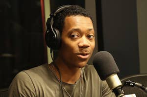 Tyler James Williams sits in a chair and does an interview in front of a microphone with headphones on