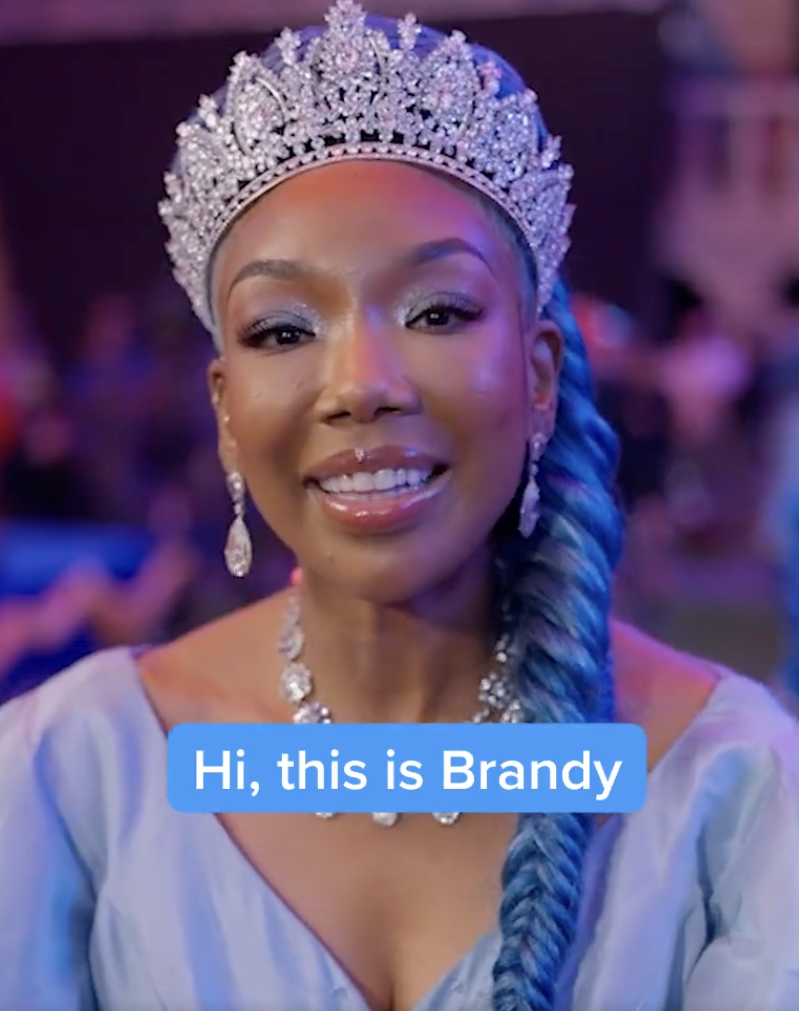 Brandy dressed as Cinderella. She&#x27;s wearing an ornate tiara and a long blue braid