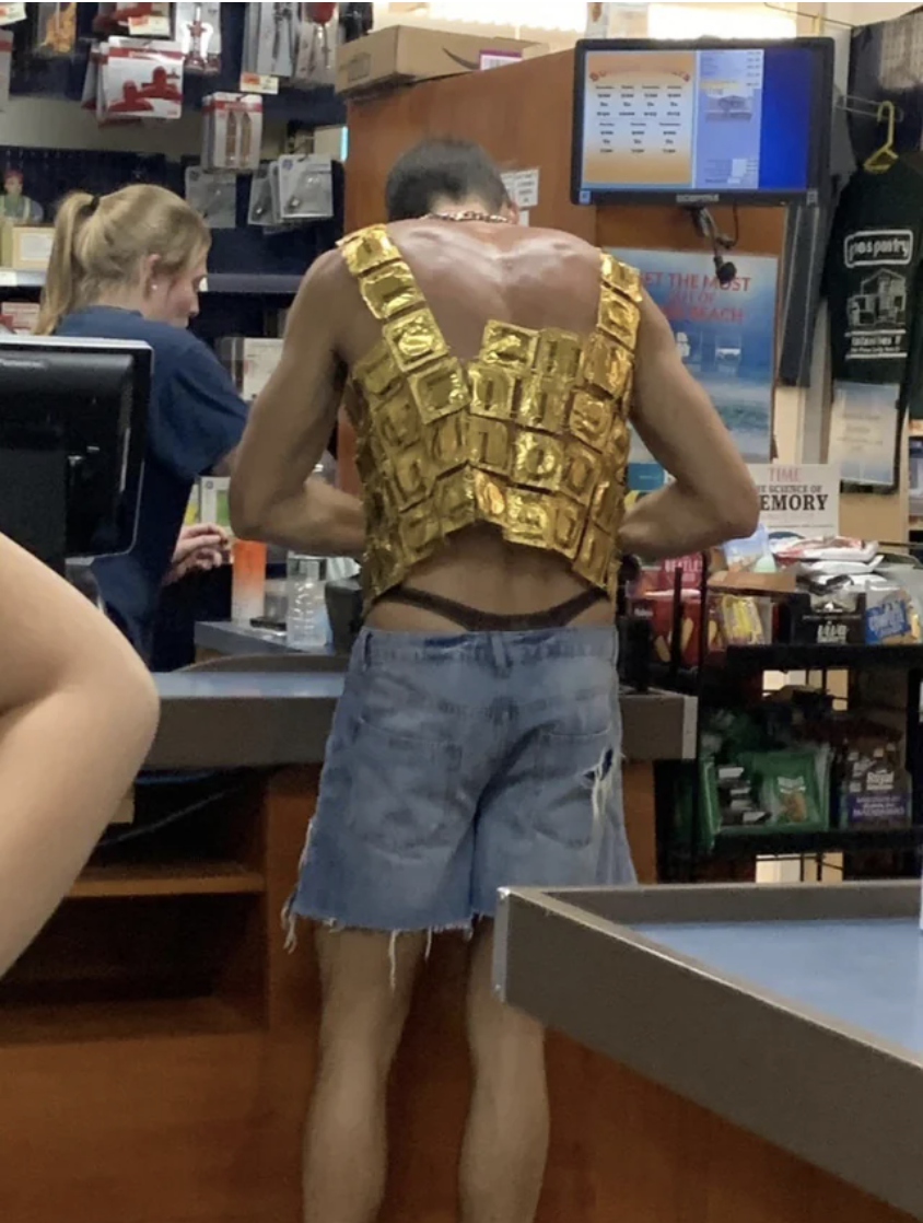 Person at a counter in cut-off jeans and a tank top made out of condom packs
