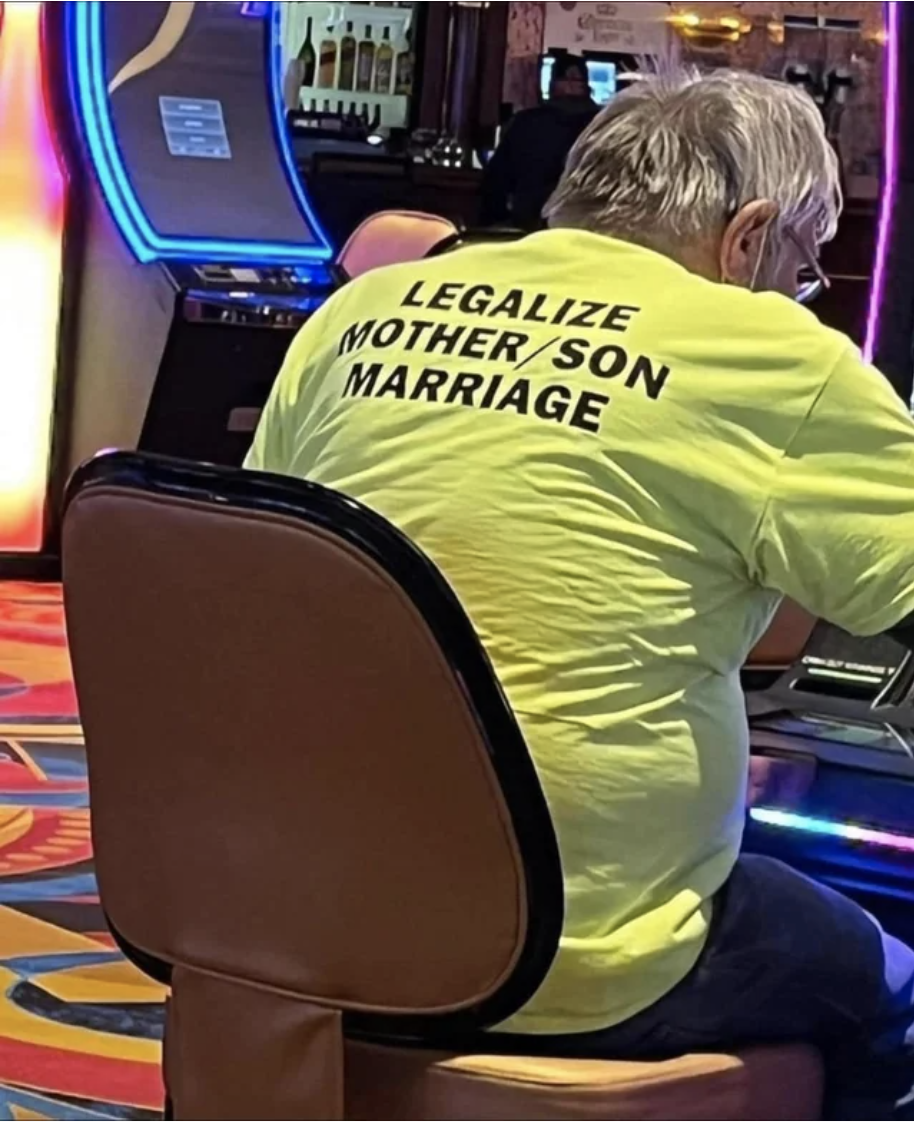 A person sitting in a casino with a T-shirt that says &quot;Legalize mother/son marriage&quot; on the back