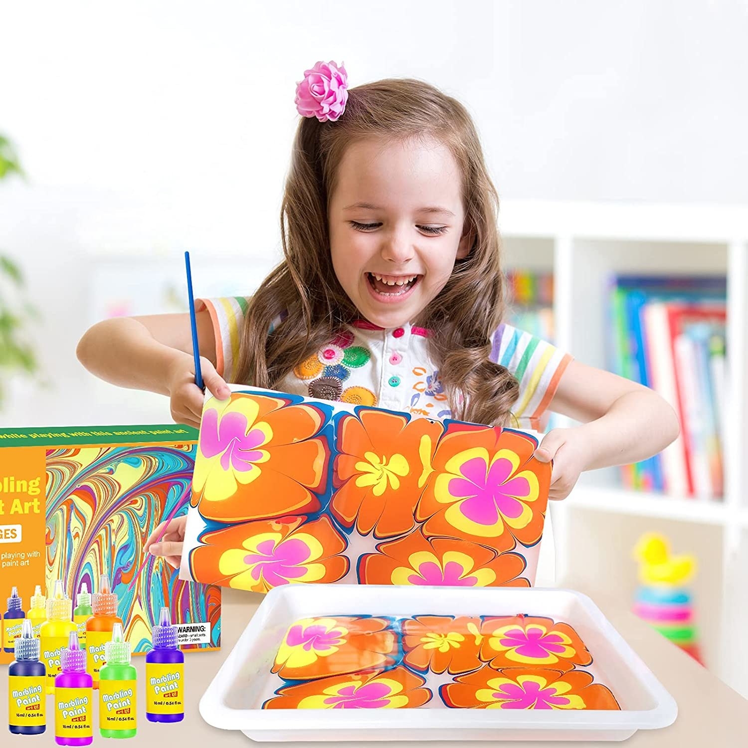 Child model holding up flower artwork from water paint set