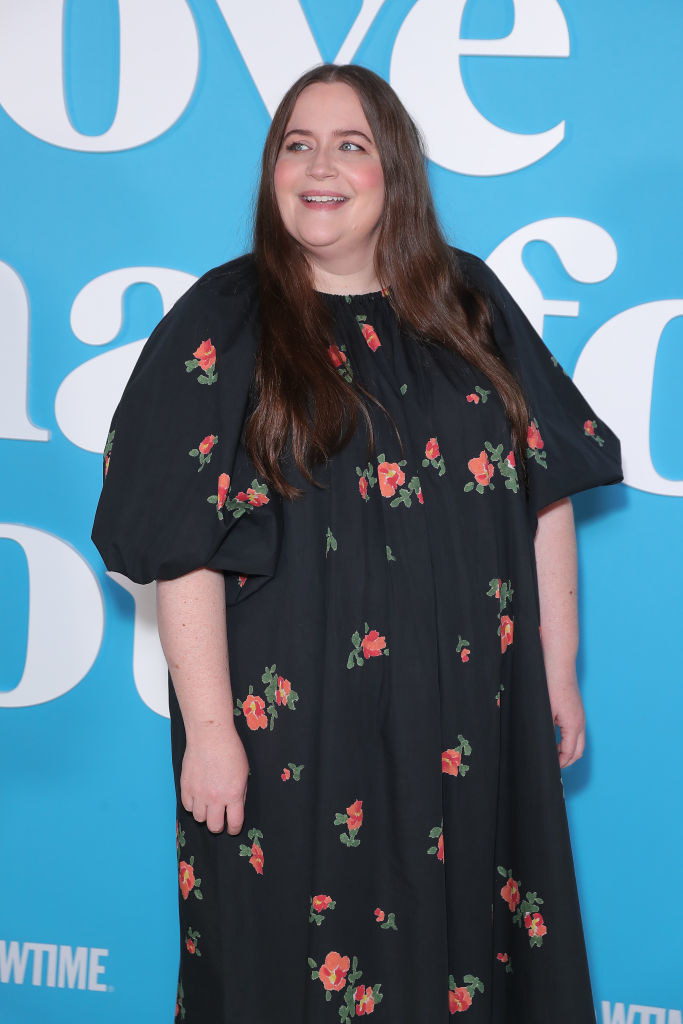 Aidy smiling in a loose, short-sleeved floral-print dress