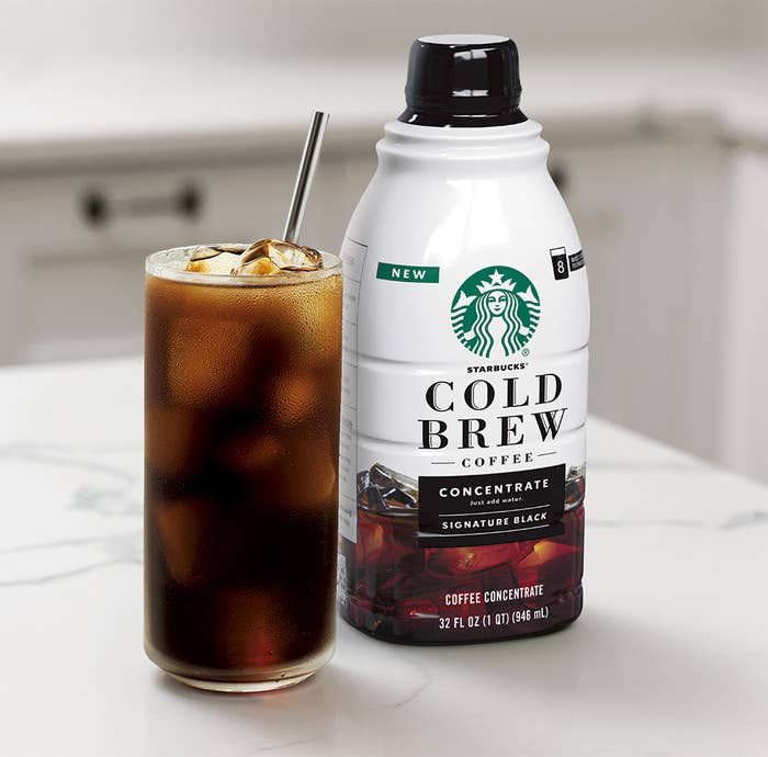 A glass of cold brew next to the bottle on a marble counter