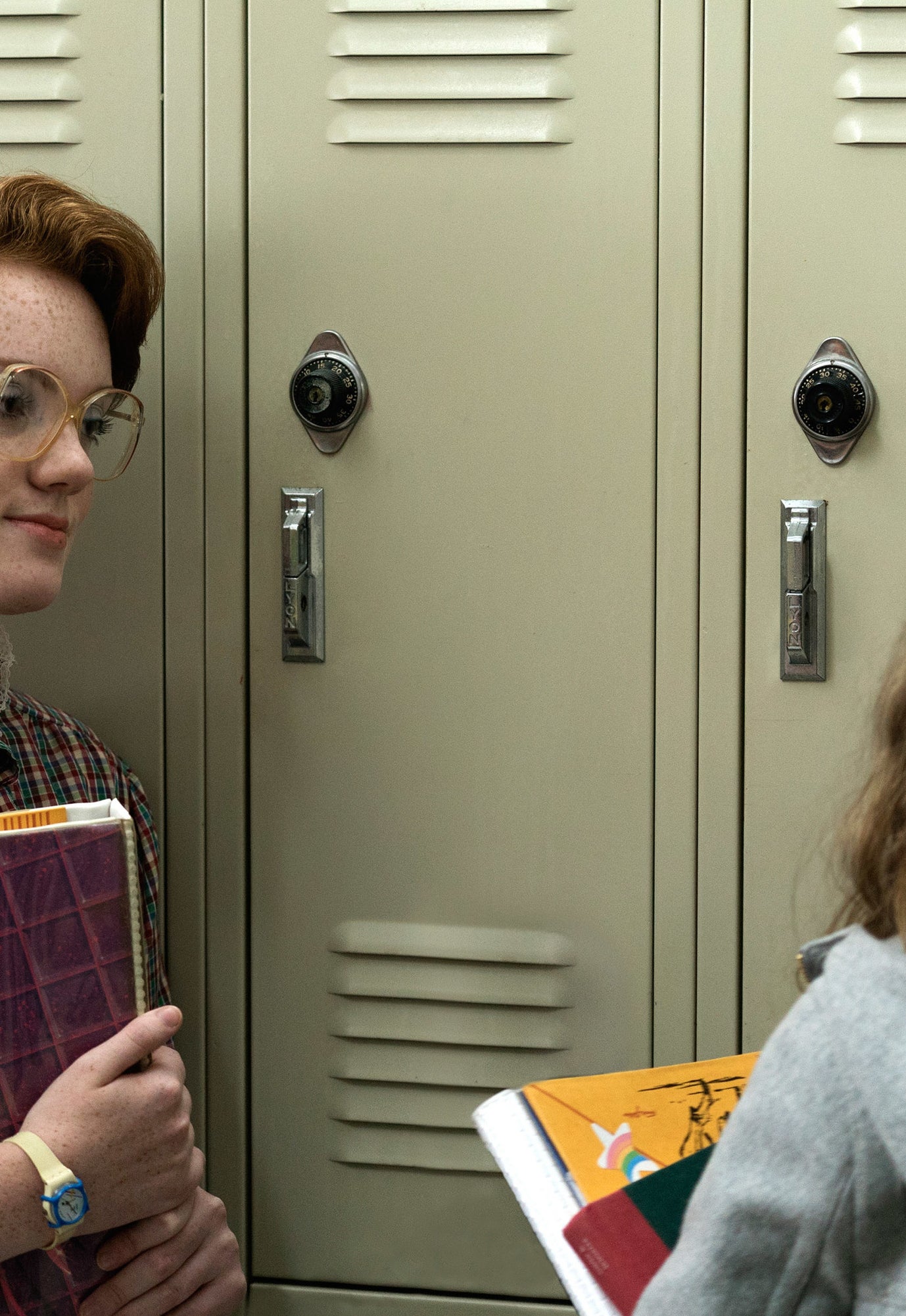 Close-up of Shannon as Barbara from Stranger Things standing next to a school locker