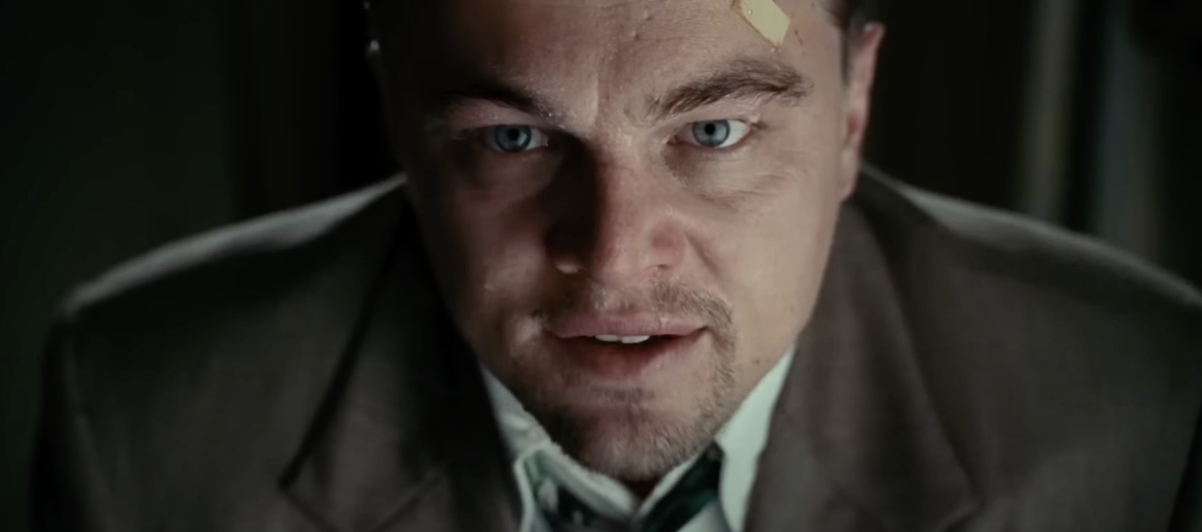 a close-up shot of Leonardo DiCaprio, who looks confused and has a bandage on his forehead