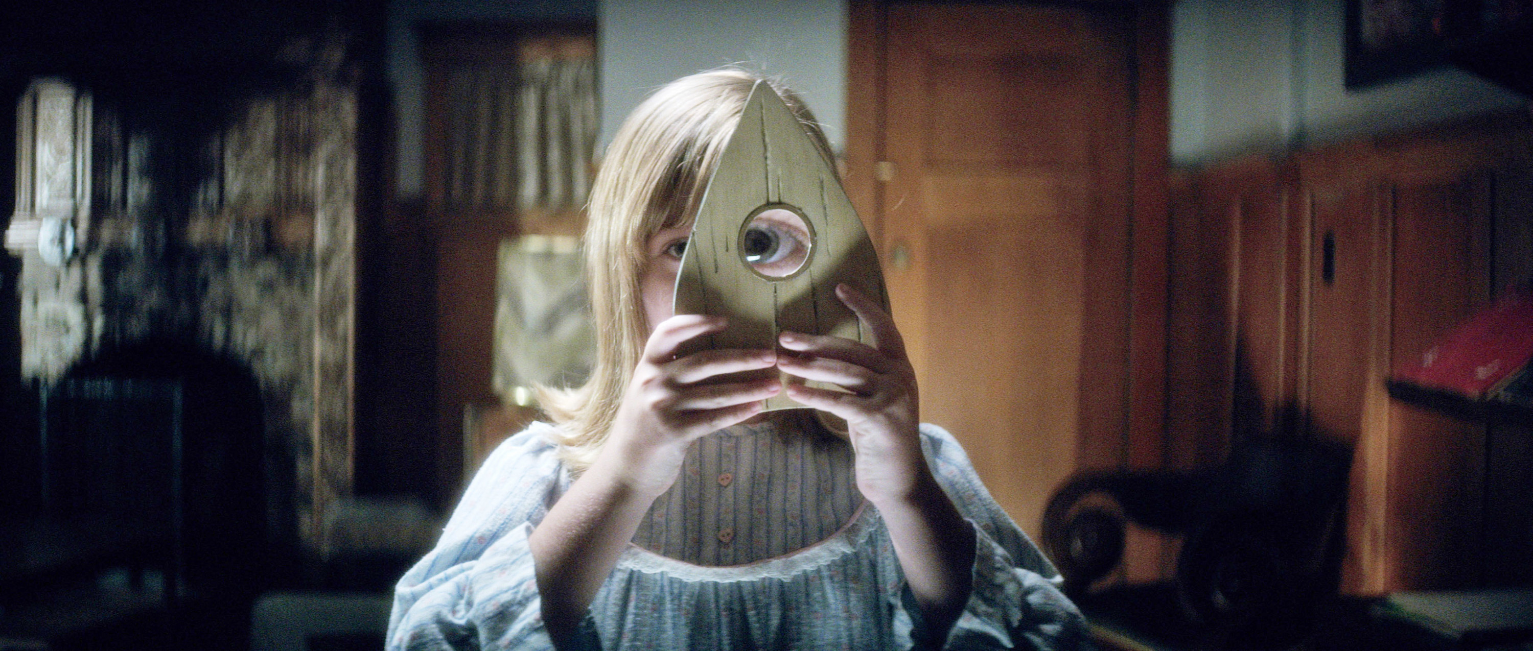 Lulu Wilson holds up a Ouija piece to her eye