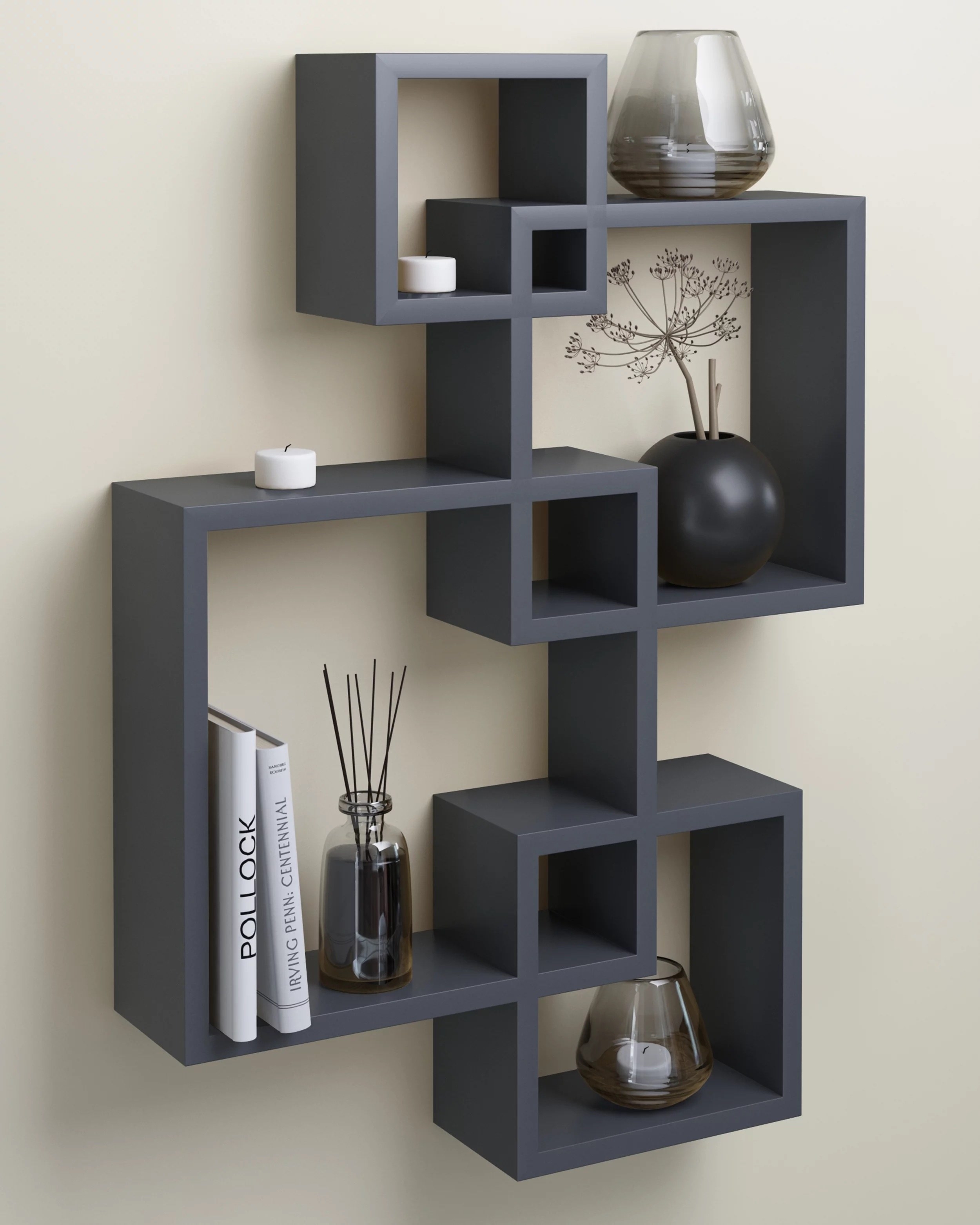 a gray four-cube hanging shelf holding books, candles, and a plant