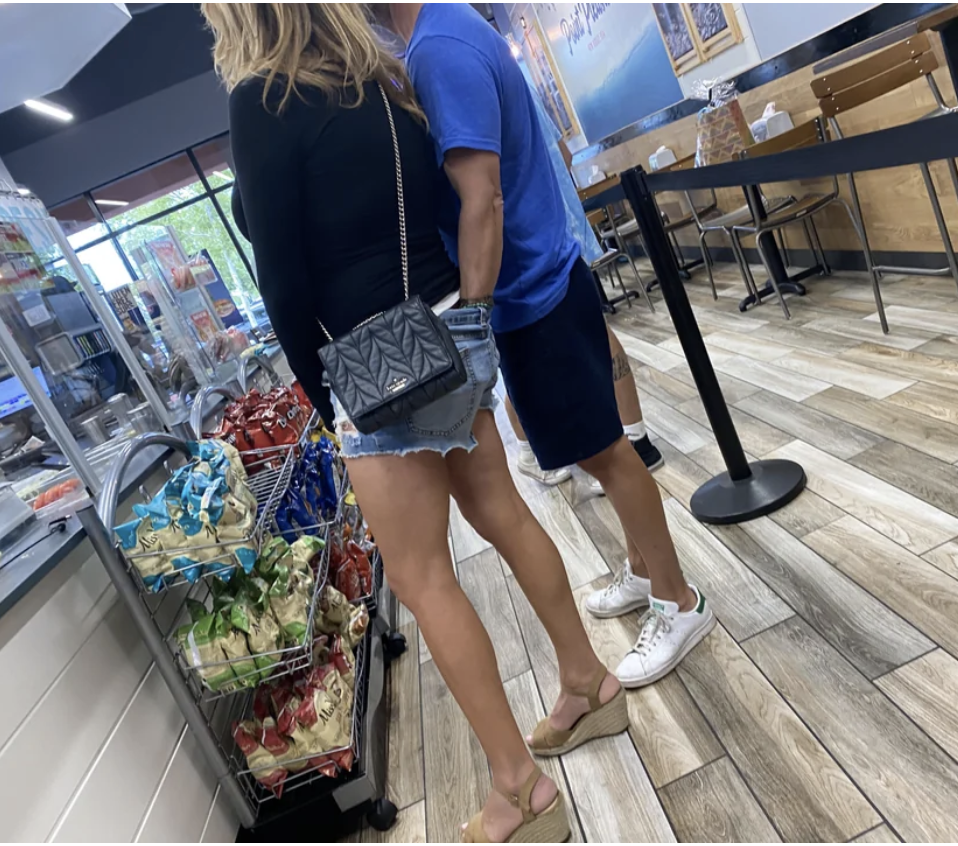 They&#x27;re standing in line at a deli; she&#x27;s in shorts, and he has his entire hand inside the back of them