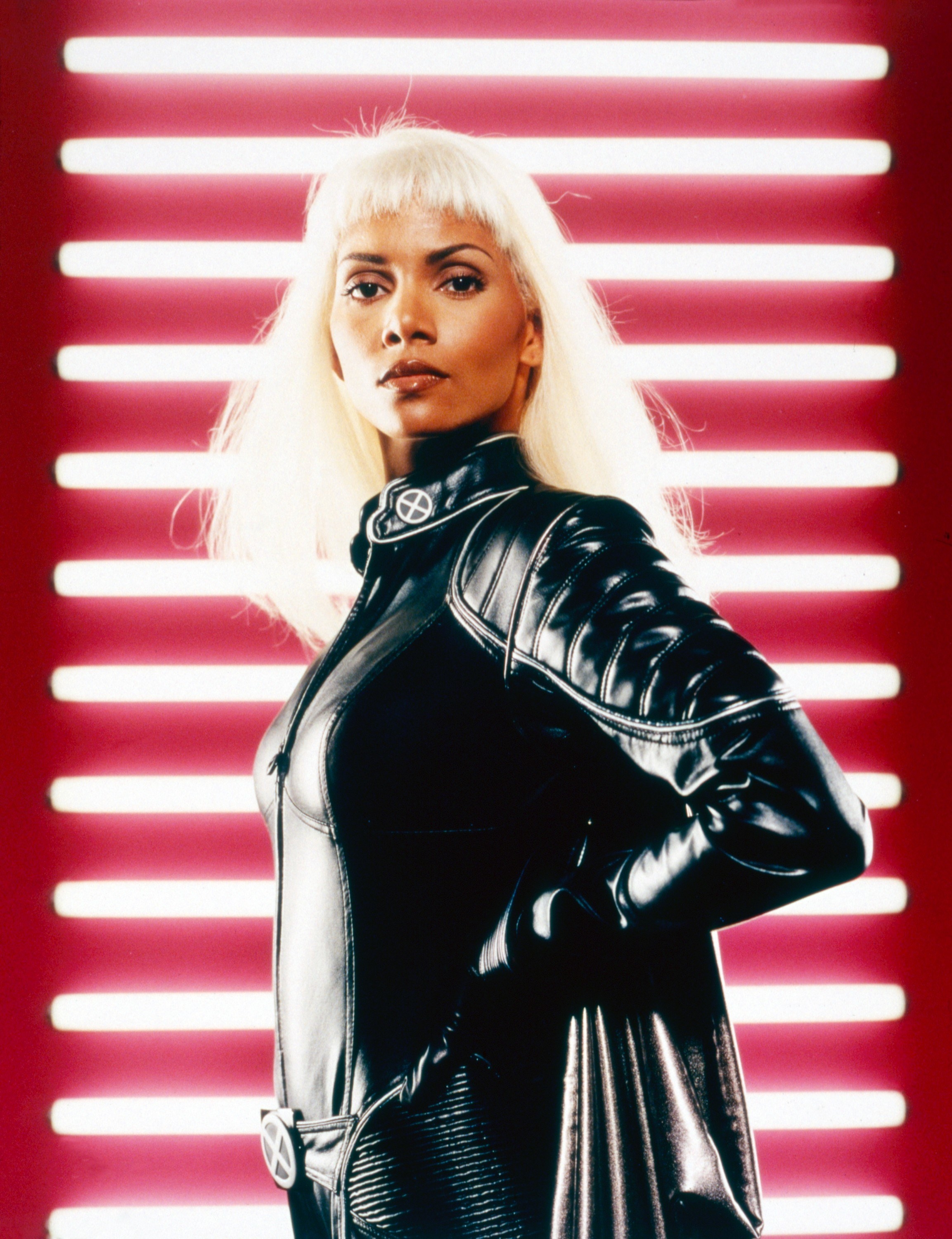 Halle as Storm with long blonde hair with bangs and wearing a leather superhero suit with cape