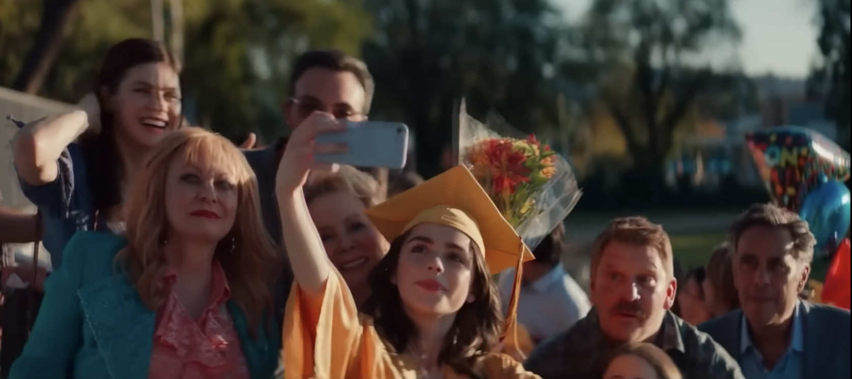 teen taking a selfie after graduation with her family