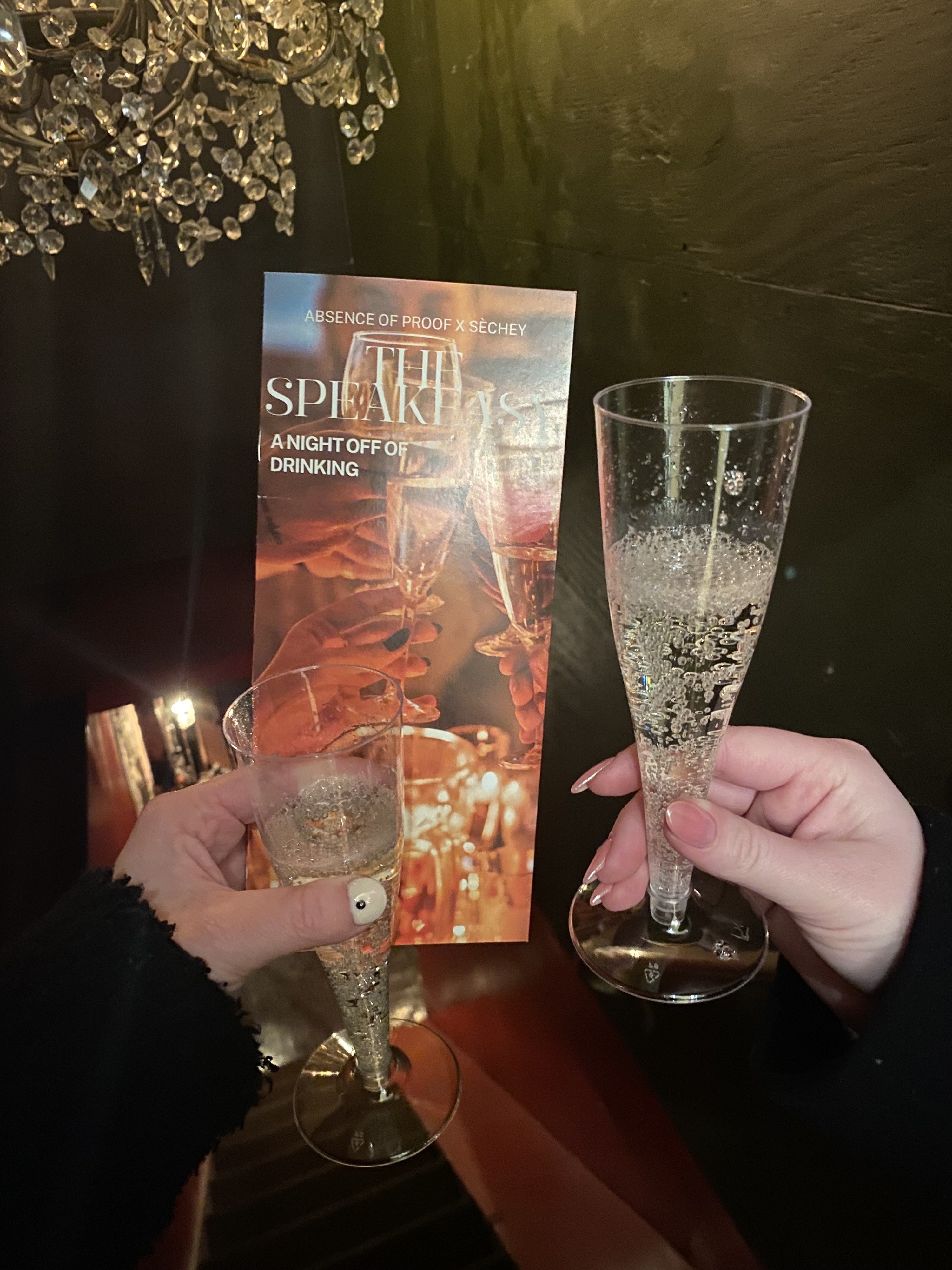 The pamphlet and two hands holding glasses of nonalcoholic champagne