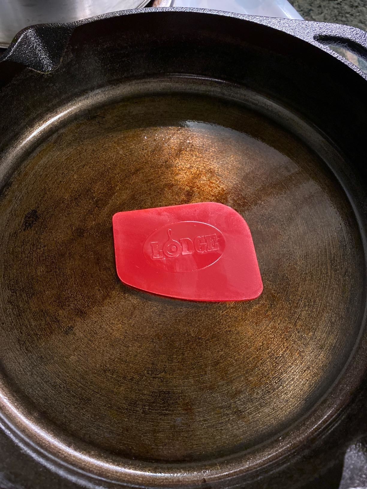 Reviewer image of red pan scraper in a cast iron pan