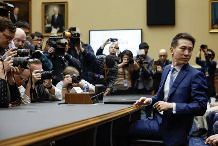 TikTok CEO Shou Zi Chew in a blue suit surrounded by press with cameras at a congressional hearing