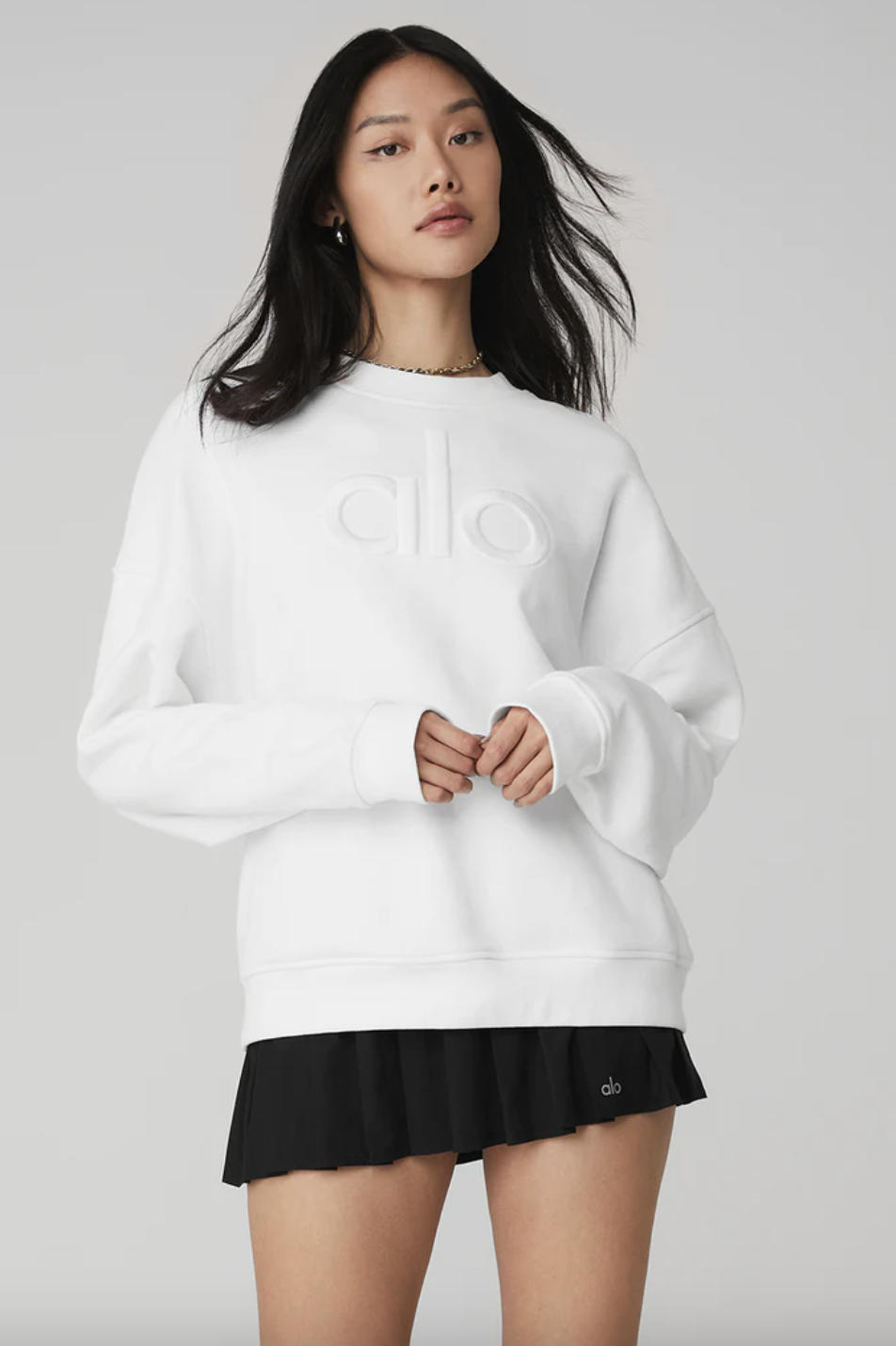 a person wearing an oversized alo sweatshirt with a skirt
