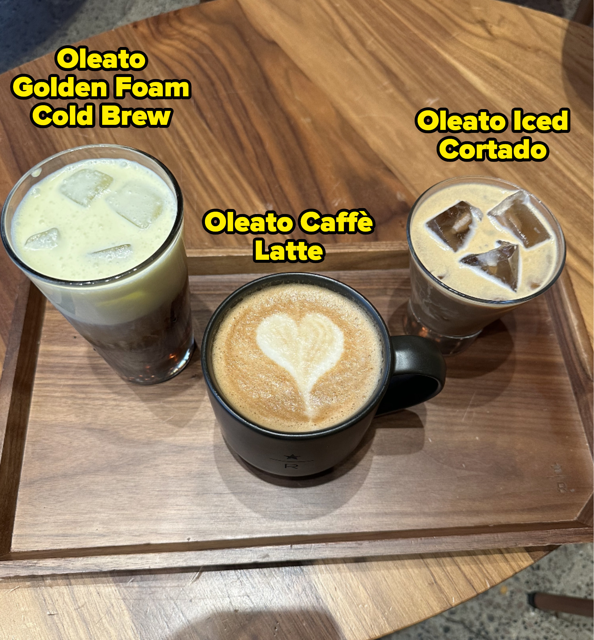 From left to right: the Oleato Golden Foam Cold Brew, the Oleato Caffe Latte, and the Oleato Iced Cortado on a wooden tray