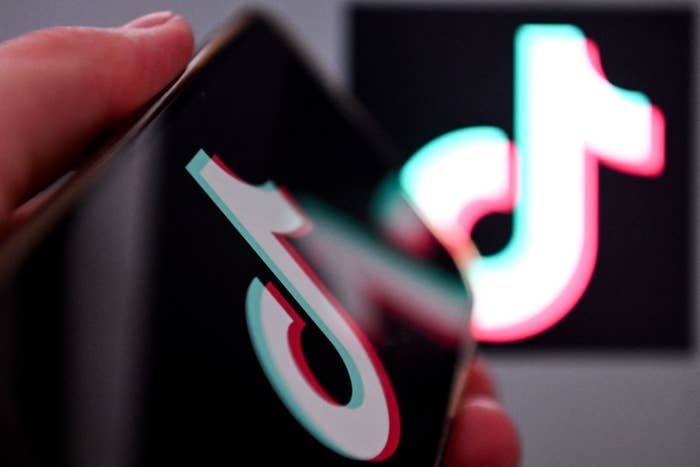 A hand holding a smartphone with the TikTok logo on the screen