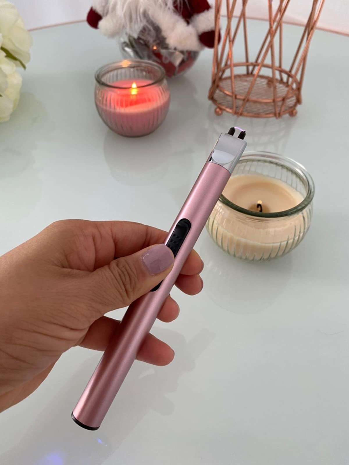 reviewer holding the pink rechargeable lighter in front of lit candle