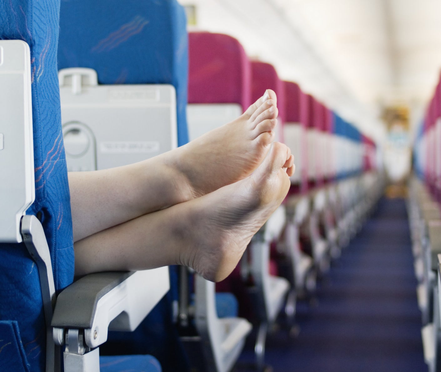 Someone&#x27;s feet hanging out of the aisle on a plane