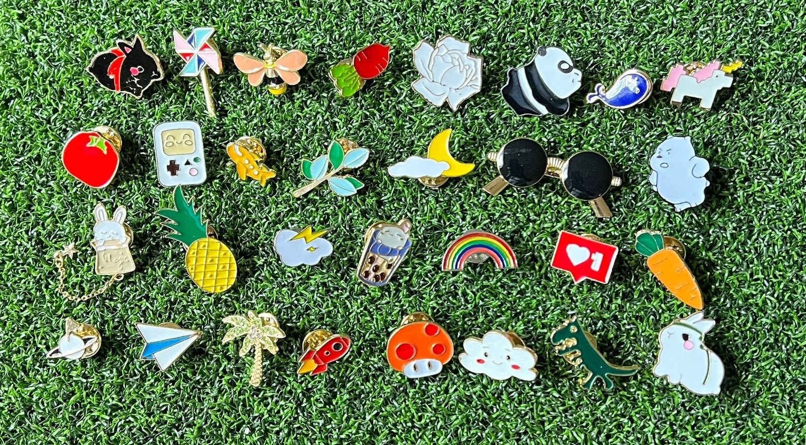 Assorted enamel pin set on grass background