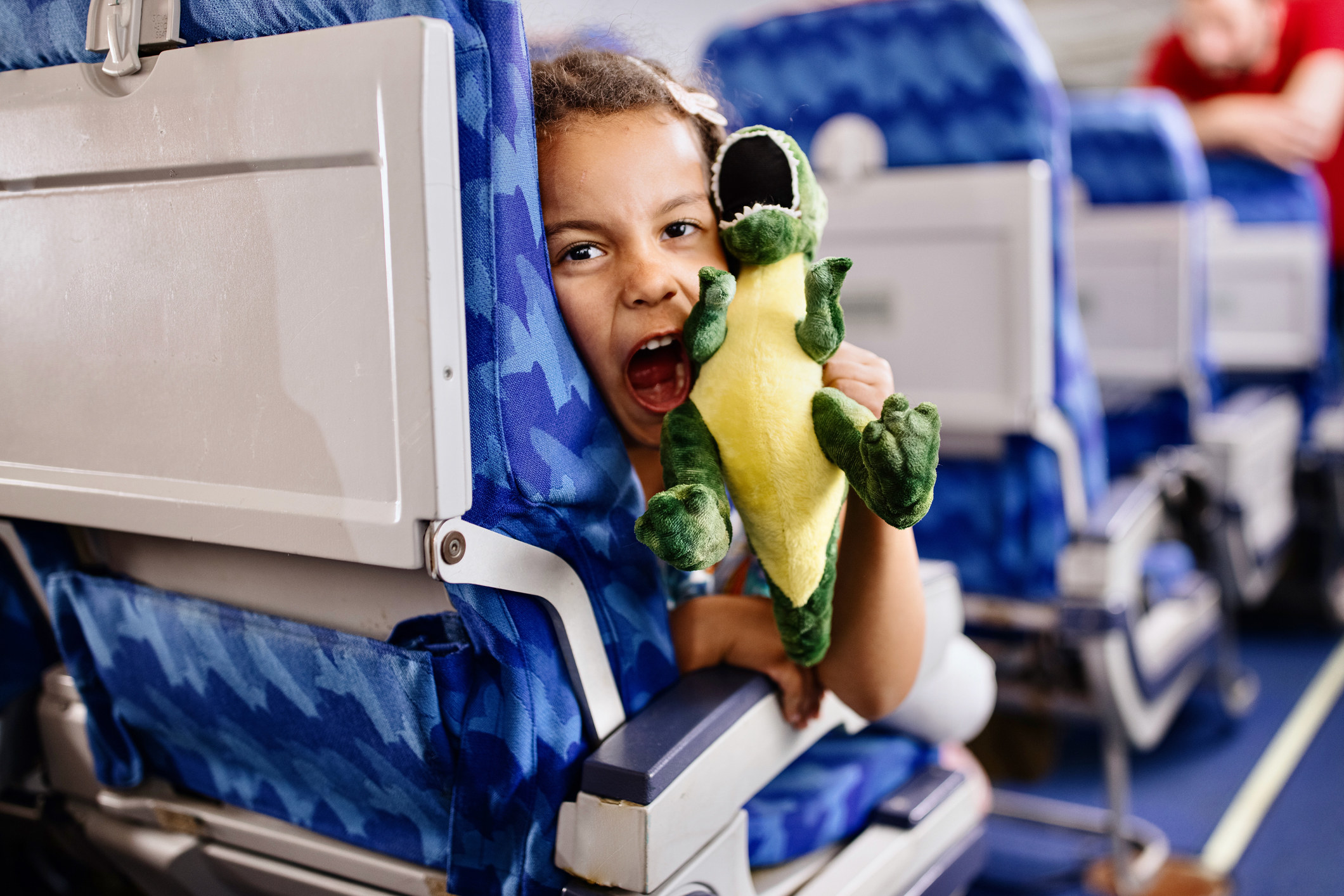 A kid on a plane with a toy dinosaur
