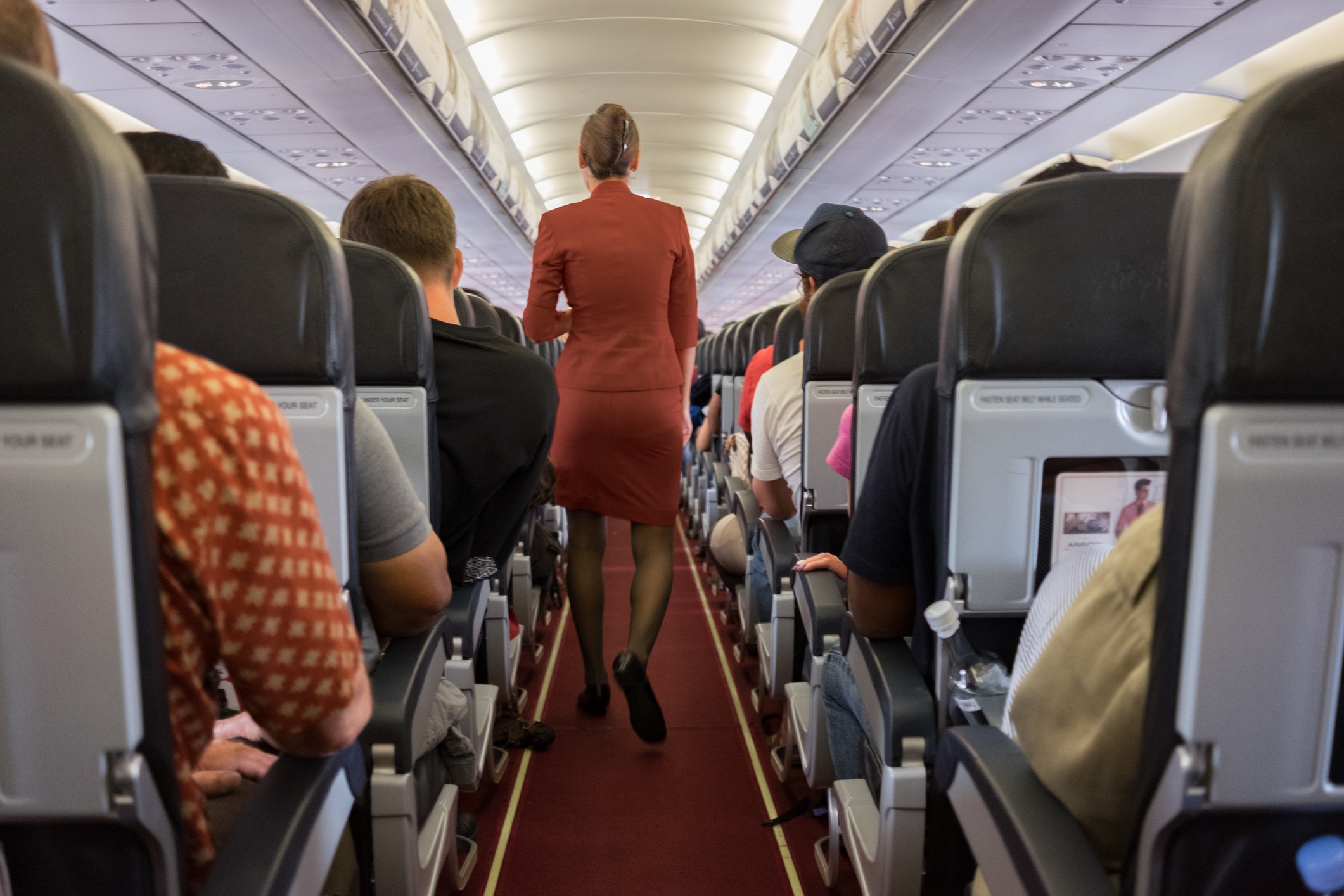 A flight attendant in the aisle of a plane