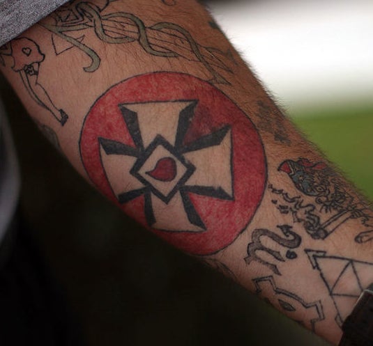 the blood drip tattoo is a cross with a diamond and blood drop in the middle