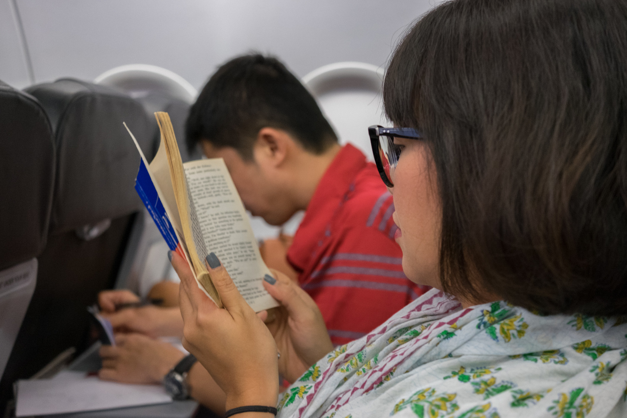 A woman reading a book on a plane